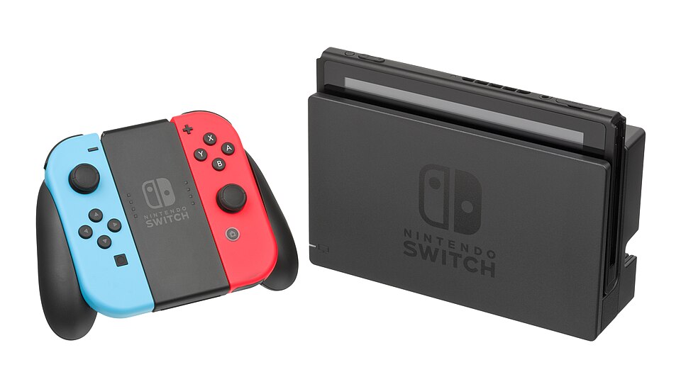 Consola Nintendo Switch en su base junto a los Joy-Con en su soporte.